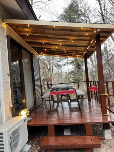 a wooden deck with a picnic table on it at おもちゃ王国と北軽井沢の大自然を満喫できる貸別荘 in Karuizawa