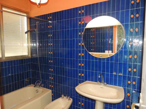 ein blau gefliestes Bad mit einem Waschbecken und einem Spiegel in der Unterkunft LE JARDIN D AURELIE in Sainte-Livrade-sur-Lot