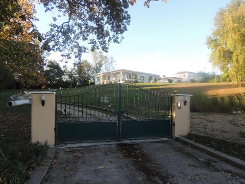 um portão numa entrada com uma casa ao fundo em LE JARDIN D AURELIE em Sainte-Livrade-sur-Lot
