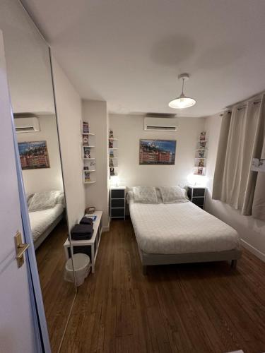 - une petite chambre avec 2 lits et un miroir dans l'établissement Villa des palmiers, à Villeneuve-sur-Lot