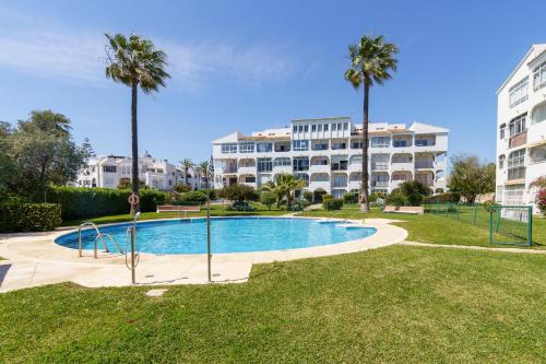 uma piscina com palmeiras e um edifício em Sunny Zoco Calahonda em Mijas Costa