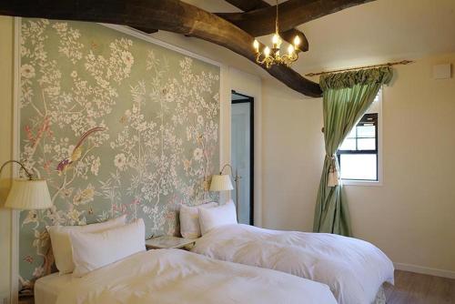 a bedroom with two beds and a wall with floral wallpaper at Kuwayama Bettei in Mitoyo