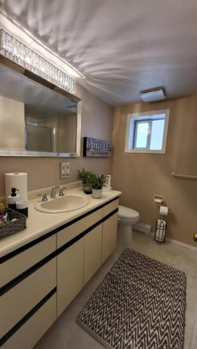 a bathroom with a sink and a mirror and a toilet at Spacious Vacataion Home in Gorgeous Neighbourhood in Victoria