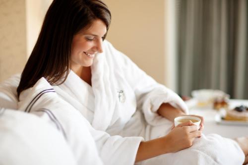 a woman in a bathrobe holding a cup of coffee at Fairmont Copley Plaza in Boston