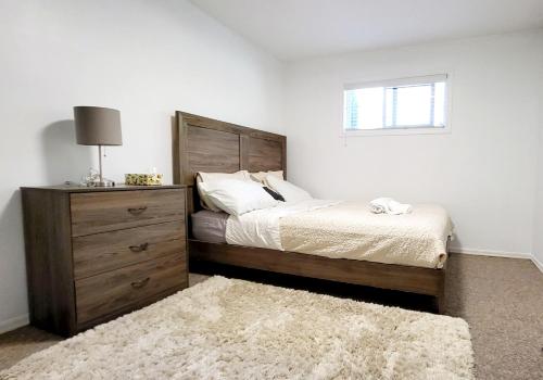 a bedroom with a bed and a dresser and a window at Spacious Vacataion Home in Gorgeous Neighbourhood in Victoria