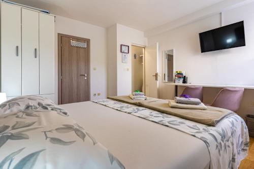 a bedroom with two beds and a flat screen tv at The Rožolina room in Cres