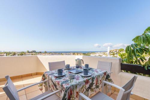 einen Tisch und Stühle auf einem Balkon mit Strandblick in der Unterkunft Sunset Seaview Corner With Pool in Estepona