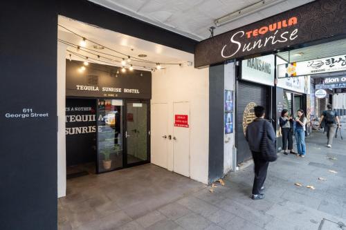 a man walking down a sidewalk outside of a store at Tequila Sunrise Hostel Sydney in Sydney