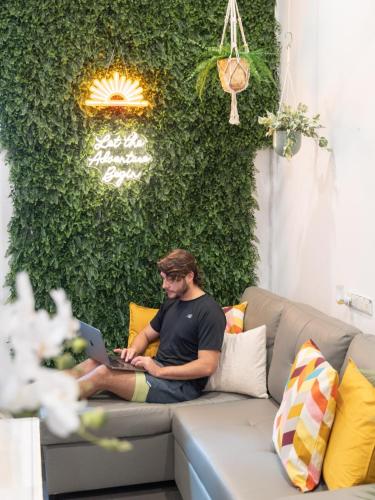 a man sitting on a couch with a laptop at Tequila Sunrise Hostel Sydney in Sydney