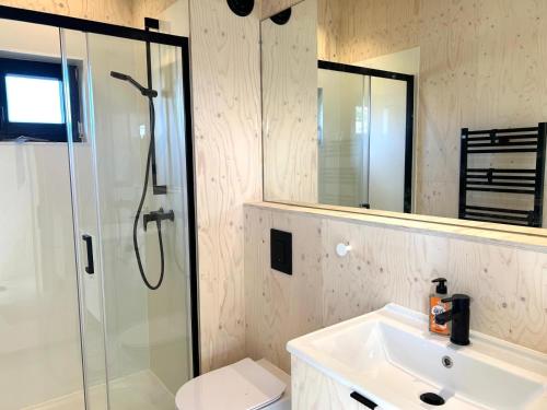 ein Bad mit einer Dusche, einem Waschbecken und einem Spiegel in der Unterkunft Hello Zeeland - Tiny House Zeeuwse Liefde 5 in Westkapelle