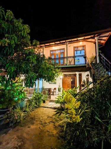 a white house with a balcony at night at The Emerald Guest House & Villa in Unawatuna