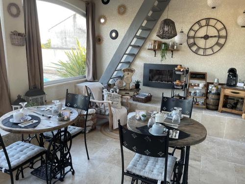 a dining room with tables and chairs and a staircase at Maison d'hôtes L'air d'antan in Bias