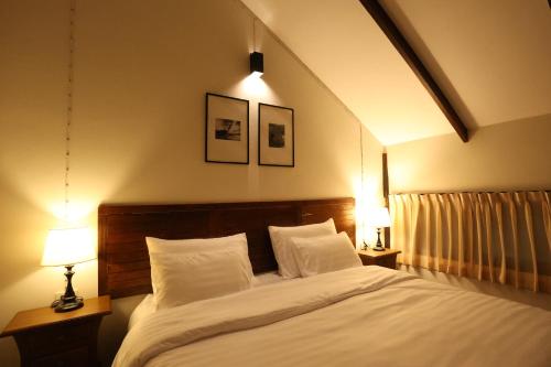 a bedroom with a large white bed with two lamps at Baanrongmai Canal Front Cafe & Homestay in Bang Chak