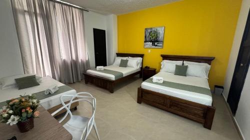 Habitación de hotel con 2 camas y mesa en HOTEL CATALUÑA - SOLUCIONES HOTELERAs en Pereira