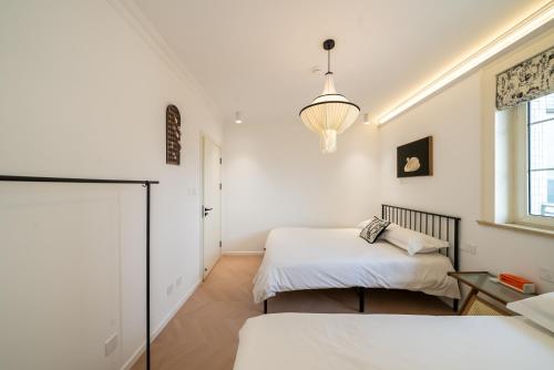 a white room with two beds and a window at Shanghai Yi Du B&B -Family - Friendly Suite Close to People's Square and Subway in Shanghai