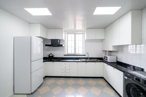 a white kitchen with black counters and white appliances at Shanghai Yi Du B&B -Family - Friendly Suite Close to People's Square and Subway in Shanghai