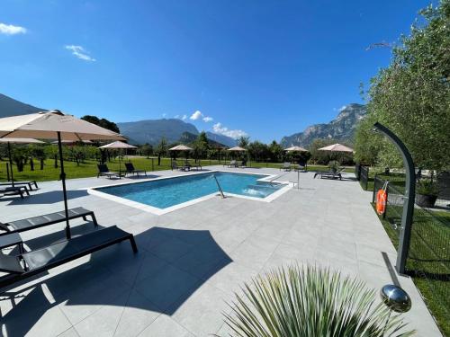 una piscina con mesas y sombrillas en un parque en Arcovacanze, en Arco