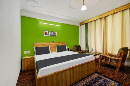 1 dormitorio con cama y pared verde en OYO Asha Cottage, en Manali