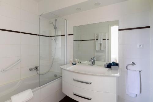 a white bathroom with a sink and a shower at Louison Appart & Suite in Quiberon