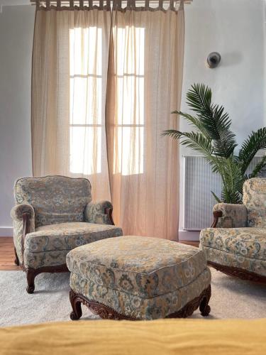 a living room with two chairs and a ottoman at Le Clos Gabrielle in Châtellerault