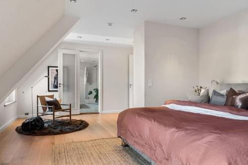 a bedroom with a large bed and a chair at Exclusive Penthouse with Terrace in Bergen