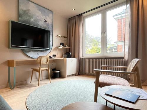 uma sala de estar com uma televisão de ecrã plano na parede em Romantik Hotel Kieler Kaufmann em Kiel