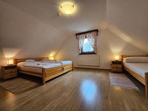 a attic bedroom with two beds and a window at Drevenice Zuberec in Zuberec