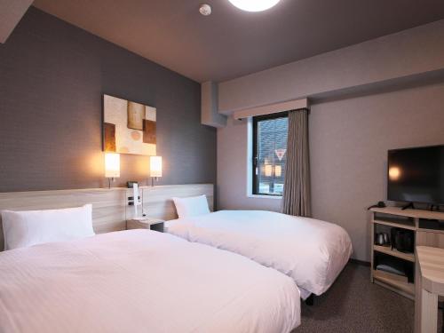 pokój hotelowy z 2 łóżkami i telewizorem w obiekcie Hotel Route-Inn Toyama Ekimae w mieście Toyama