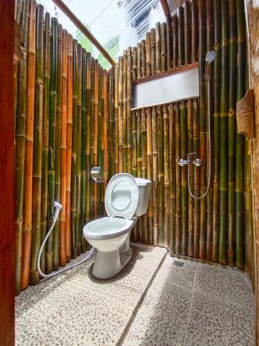a bathroom with a toilet and bamboo walls at Bamboo Sanctuary Pancawati Resort Bogor in Ciherangsating