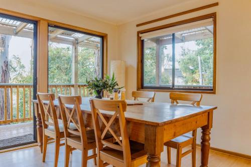 uma sala de jantar com uma mesa de madeira e cadeiras em Fern House em Wye River