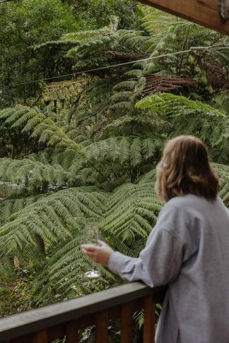 a woman standing on a balcony looking at a plant at Fern House in Wye River