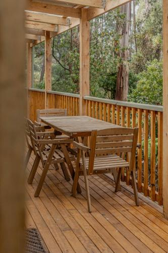 a wooden table and benches on a wooden deck at Fern House in Wye River