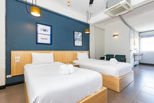 two beds in a room with a blue wall at Riverview Residence in Bangkok