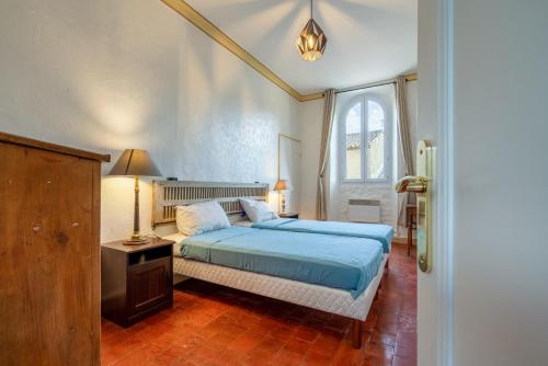 een slaapkamer met een blauw bed en een raam bij Mas Côté Cour in Maubec