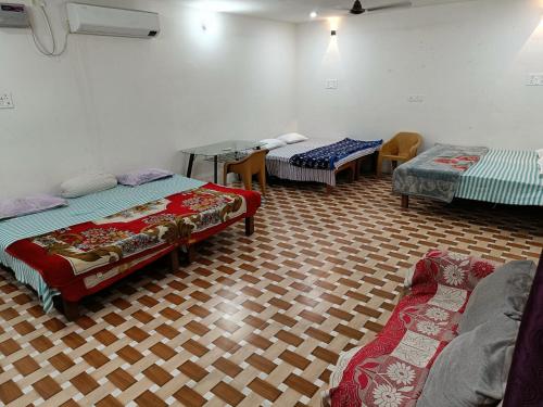 Green stay homestay في Rāmnagar: غرفه فيها ثلاث اسره وكراسي