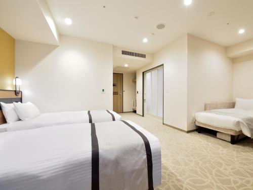 a hotel room with two beds and a couch at Hotel Elcient Osaka Umeda in Osaka