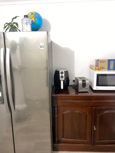 eine Küche mit einem Kühlschrank aus Edelstahl und einer Mikrowelle in der Unterkunft YnY Guest house in Waterford