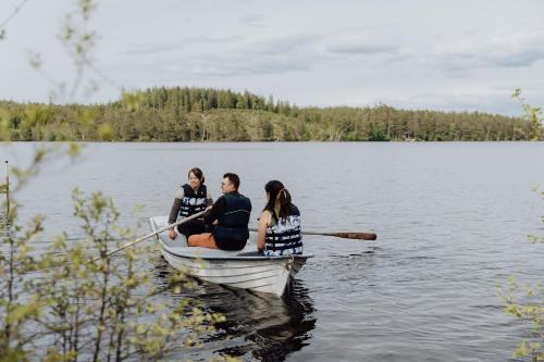 three women sitting in a boat on a lake at Trakt Forest Hotel Skogssviter in Holsbybrunn