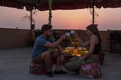 mężczyzna i kobieta siedzący przy stole z kubkiem w obiekcie Explore Hostel Life Jaisalmer w mieście Jaisalmer