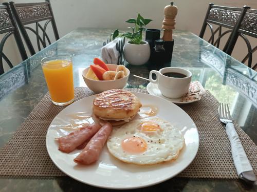 ein Teller mit Frühstücksessen mit Wurst, Bagel und Orangensaft in der Unterkunft HOTEL BLUE COSTA Panama in Panama-Stadt