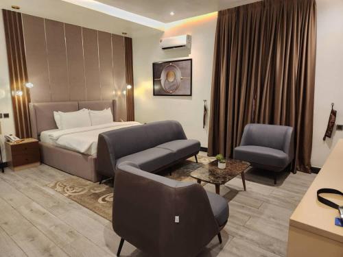 AVIEL SUITES AND HOTEL في Rubuchi: غرفة الفندق بسرير واريكة وكرسي