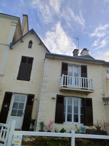 une maison blanche avec une clôture blanche devant elle dans l'établissement La bicheraie, à Arromanches-les-Bains