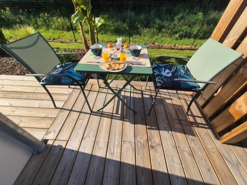 a table and two chairs on a deck with drinks at La grange de Karine et Philippe in La Clisse