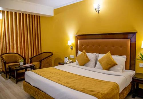 una habitación de hotel con una cama grande con paredes amarillas en Hotel Dreamland Inn, en Zirakpur