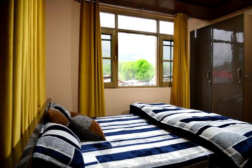 two beds in a room with a window at Hotel Inabat Residency in Srinagar