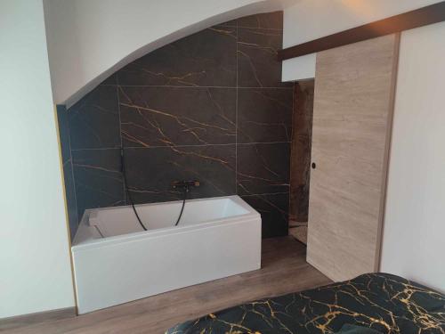 La salle de bains est pourvue d'une baignoire blanche et d'un mur en carrelage noir. dans l'établissement Maison au calme pour 8 personnes à 2 pas du château d Anjou, à Anjou