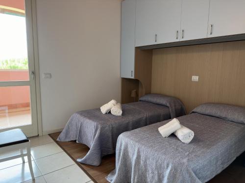 una camera con due letti con asciugamani di Airone Bianco Residence Village a Lido delle Nazioni