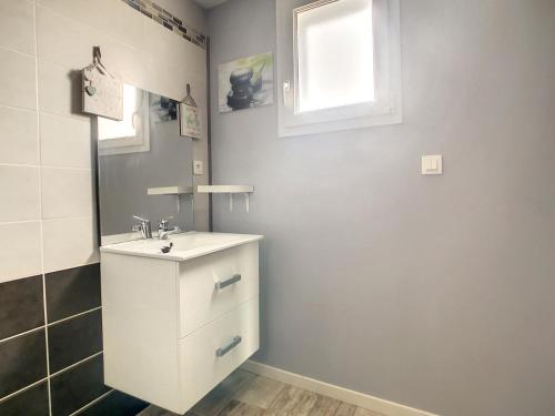 une salle de bain avec un lavabo blanc et une fenêtre dans l'établissement Le clos de Salles, à Salles-sur-Mer