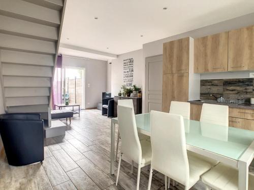 une cuisine avec une table en verre et des chaises blanches dans l'établissement Le clos de Salles, à Salles-sur-Mer