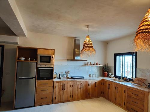 a kitchen with wooden cabinets and a stainless steel refrigerator at Villa Nour Kélibia in Kelibia